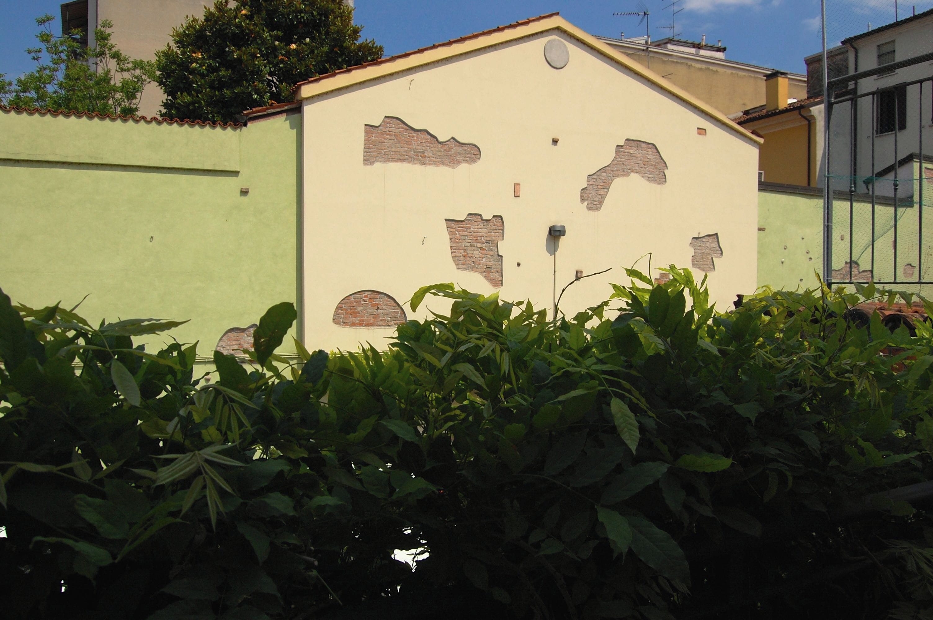 A building with a light green exterior and a beige facade with brickwork patterns.