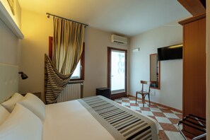Een hotelkamer met een bed, een stoel, een televisie en een raam met gordijnen.