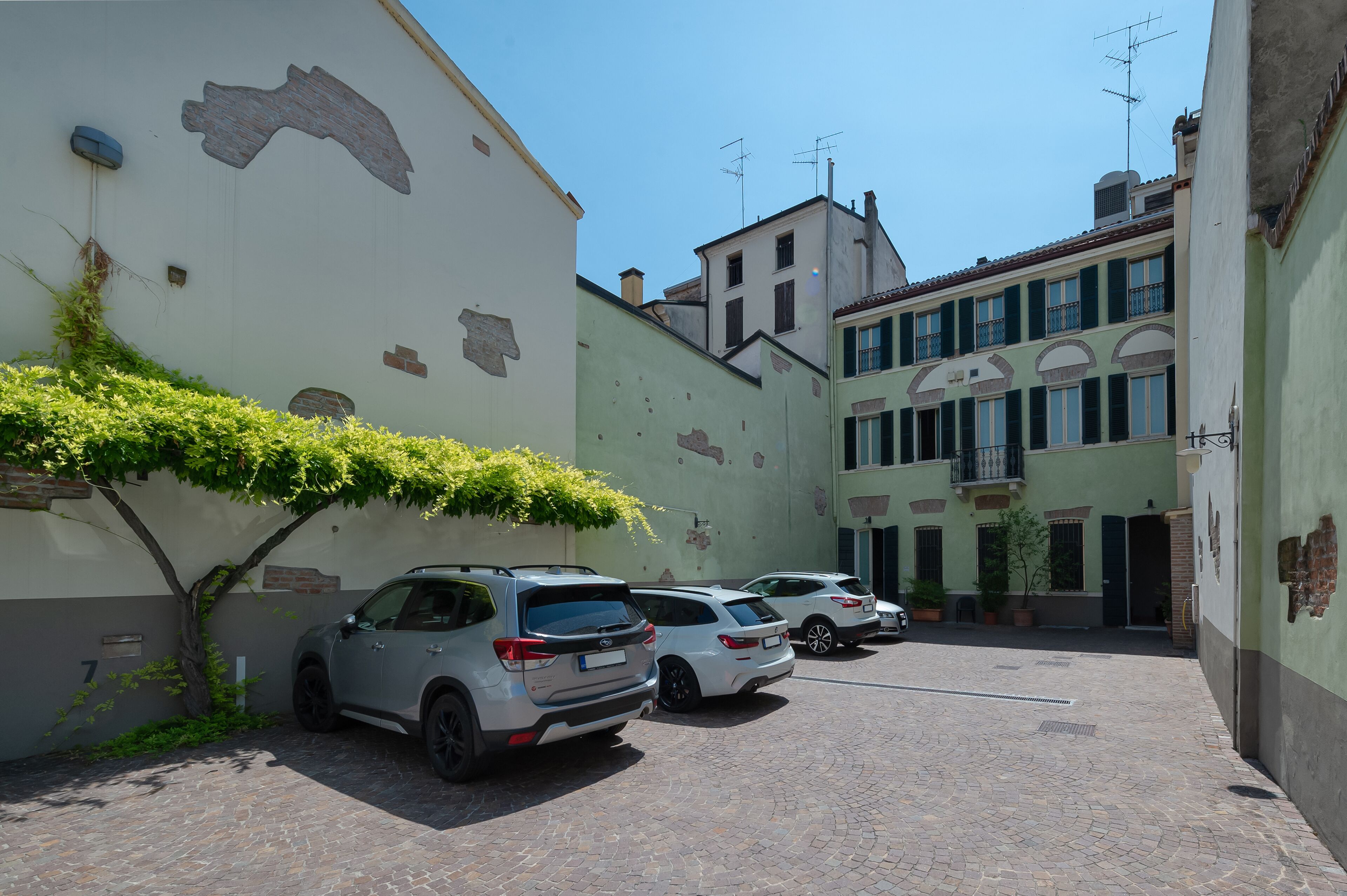A narrow street with parked cars and a building with a large mural.