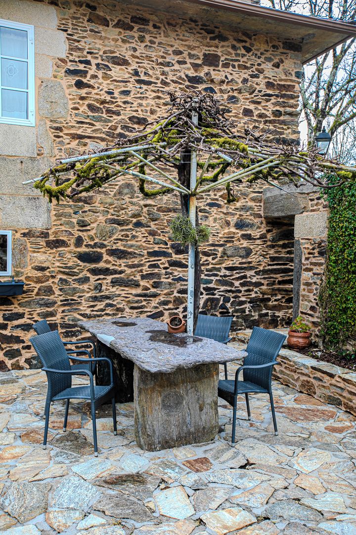 Un edificio de piedra con una pared rústica de piedra y una mesa con cuatro sillas.