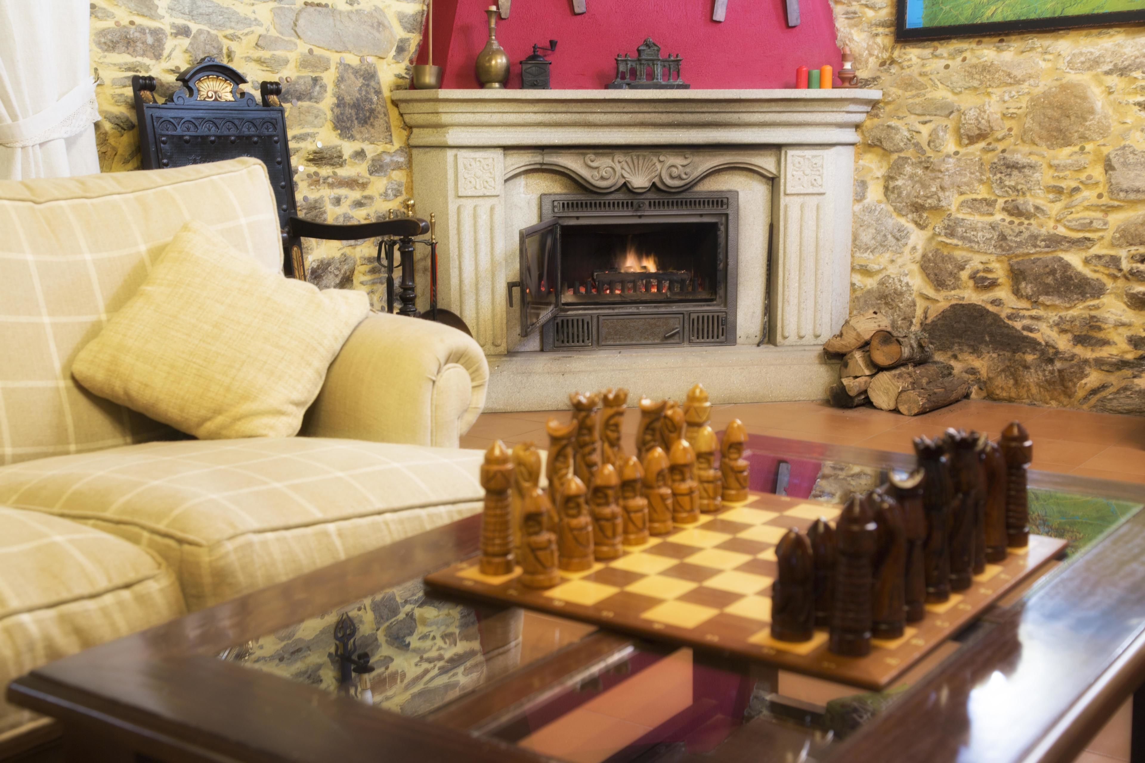 A living room with a fireplace, a chessboard, and a sofa.