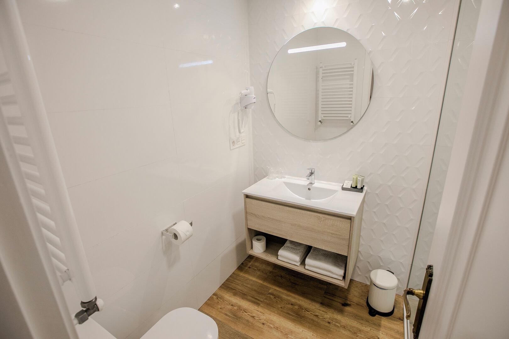 Une petite salle de bain moderne avec un lavabo blanc, un miroir et des toilettes.