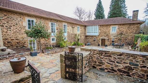 A stone building with a courtyard, outdoor seating, and potted plants.