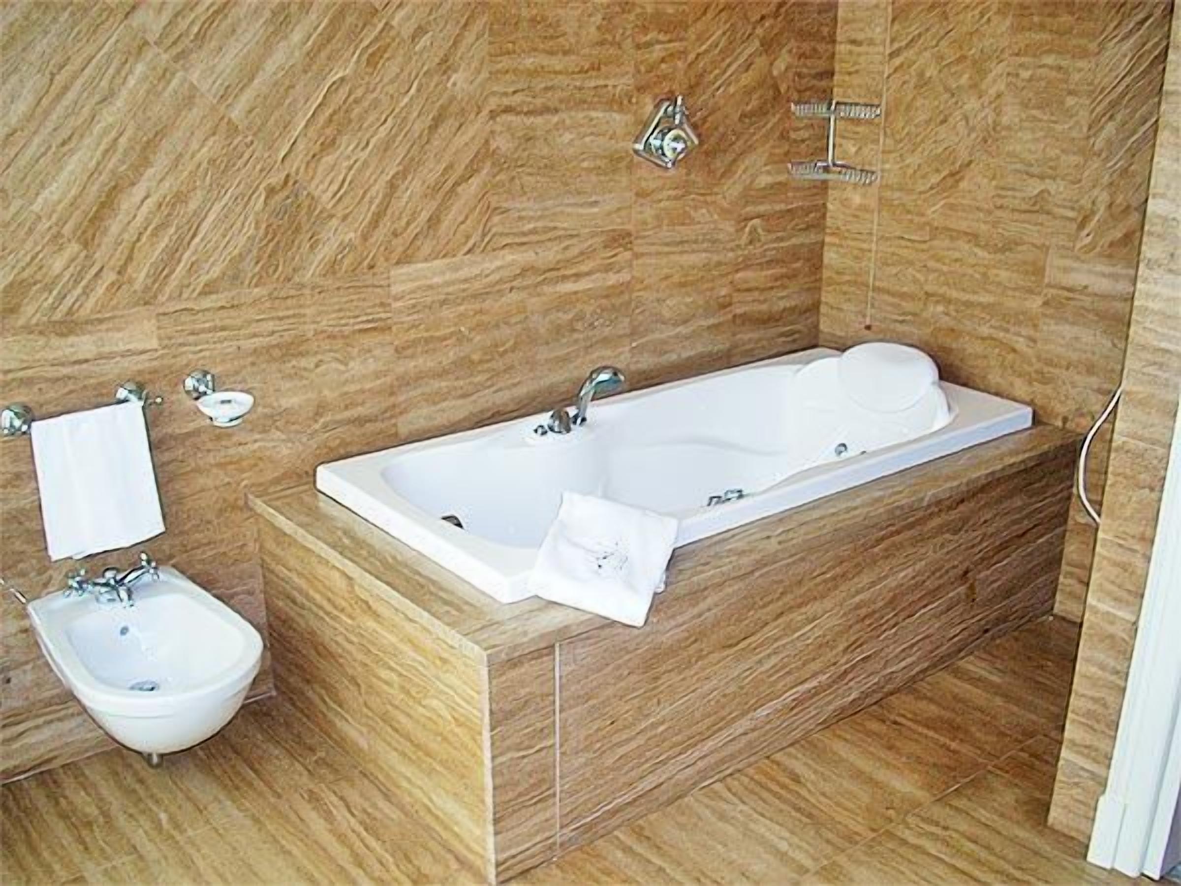 Un baño moderno con una bañera independiente, un lavamanos sobre pedestal y un perchero para toallas.