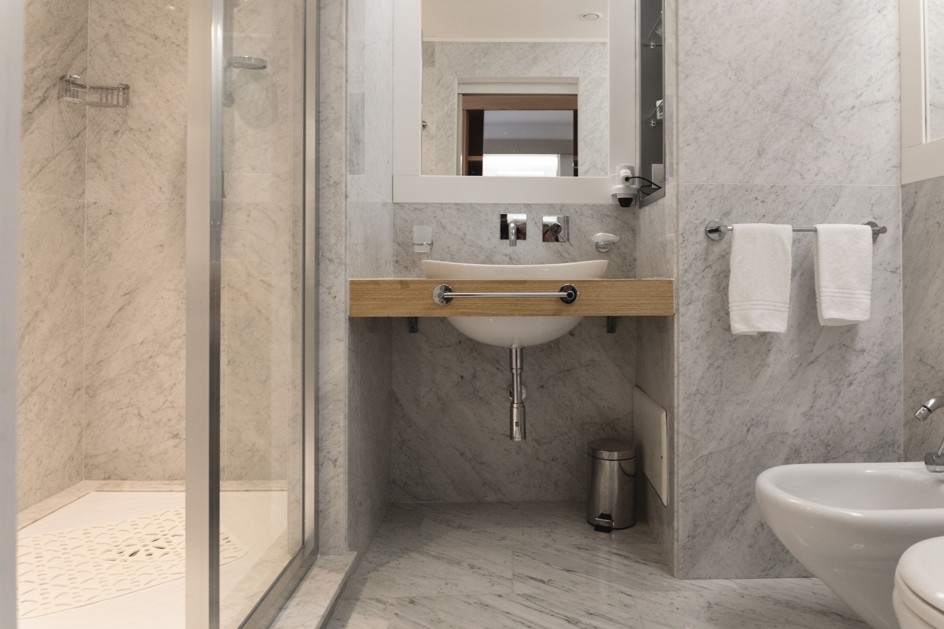 A modern bathroom with a glass-enclosed shower, a wooden vanity with a sink, and a separate toilet area.