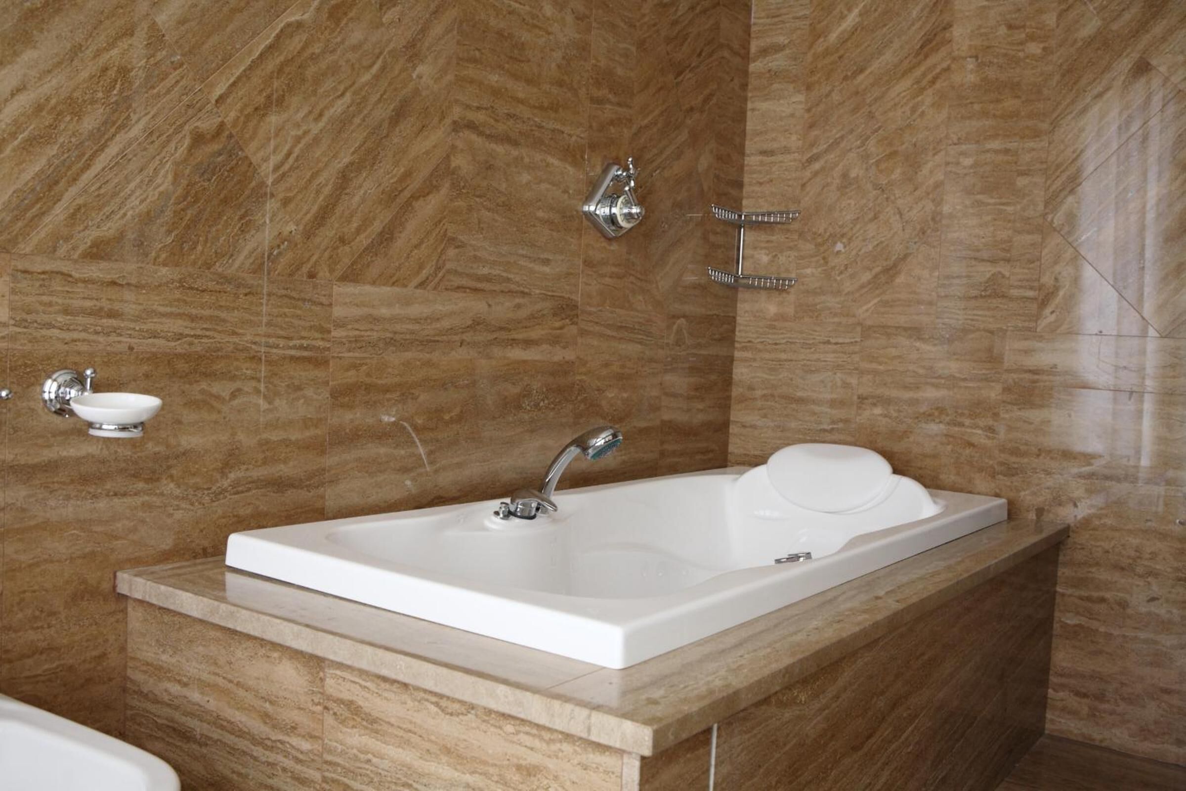 A modern bathroom with a rectangular sink, a handheld showerhead, and a wall-mounted towel rack.