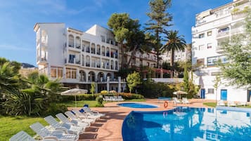 Una piscina al aire libre de temporada, sombrillas