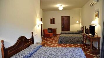 Una habitación de hotel con dos camas, un escritorio, una silla y un televisor.