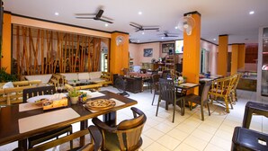 A restaurant with multiple dining areas, including a bar and a seating area with tables and chairs. - Hotel Sole (Patong)