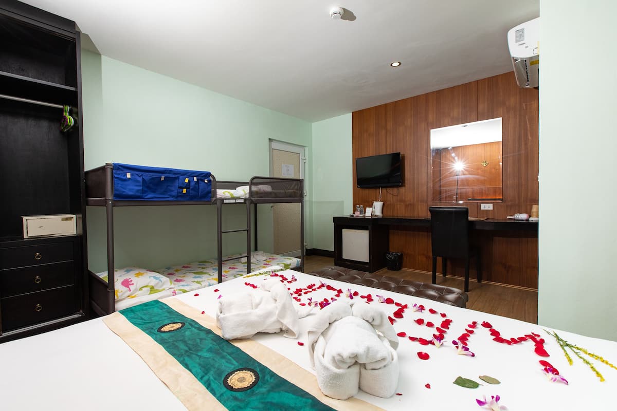 A hotel room with bunk beds, a desk, a television, and a bathroom.
