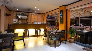 A restaurant with a bar area, chairs, tables, and a potted plant. - Hotel Sole (Patong)