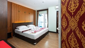 A hotel room with a wooden headboard, a bed with white linens, a red throw, and a red carpet. - Hotel Sole (Patong)