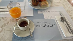 A breakfast setup with a glass of orange juice, a cup of coffee, and a plate of pastries on a table with a breakfast menu. - Hotel Harmony (Rimini)