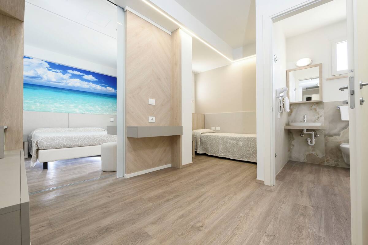 A bedroom with a bed, a bedside table, and a wall-mounted TV displaying a beach scene.