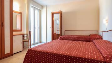 Habitació d'hotel amb dos llits, una taula de treball, una cadira i una finestra gran.