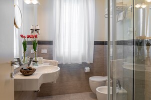 Un baño moderno con dos lavamanos, inodoro y cabina de ducha de vidrio.