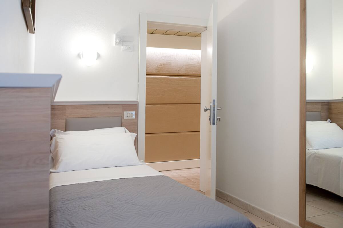 A hotel room with a bed, a wooden headboard, a bedside table, and a mirror.