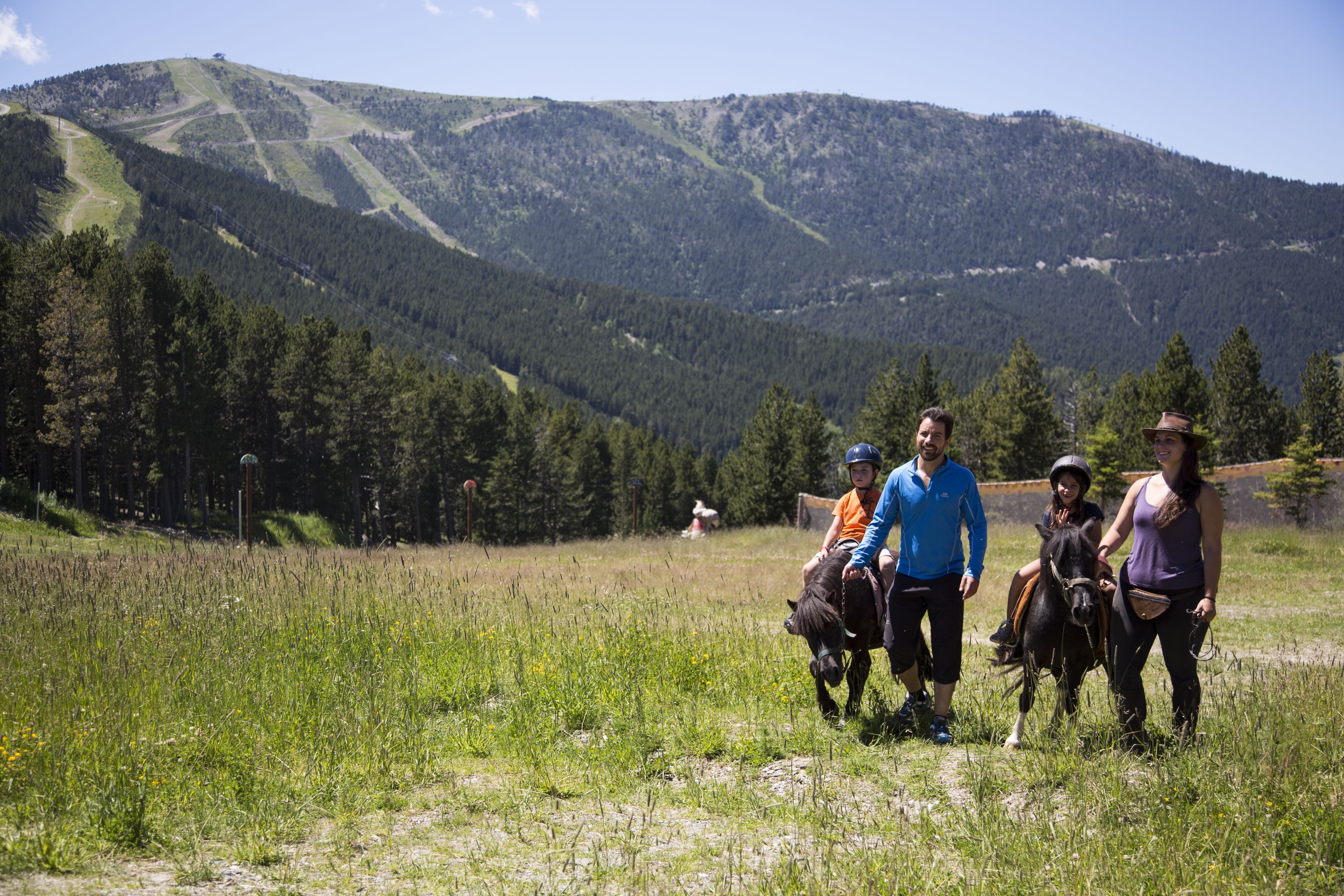 A group of people in a grassy field with a mountainous backdrop.