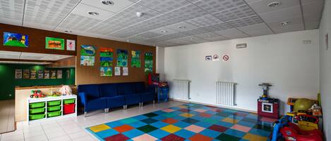 Un cuarto de juegos infantil con piso a cuadros de colores, asientos azules y varios juguetes.
