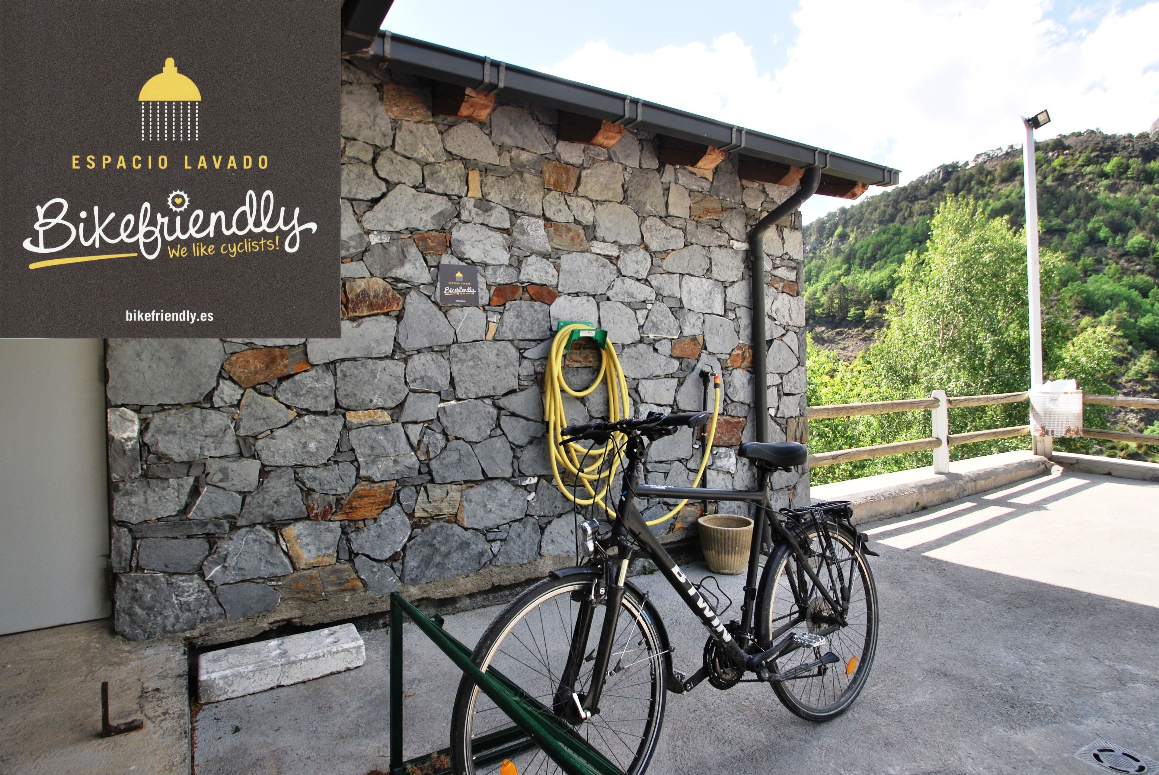 A stone wall with a bicycle and a hose coiled against it.