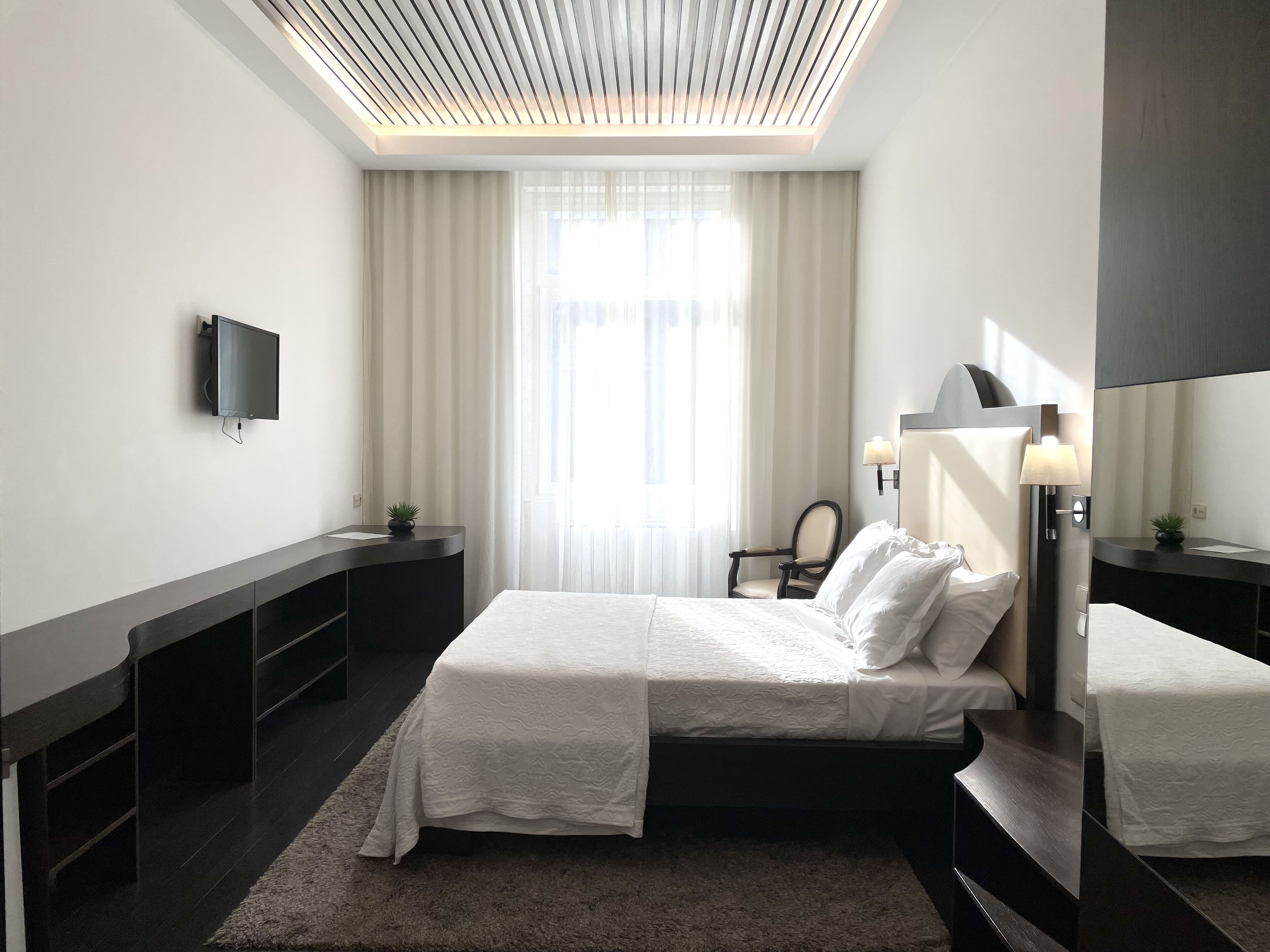 Habitación de hotel moderna con una cama grande, televisor de pantalla plana, escritorio y un espejo amplio.