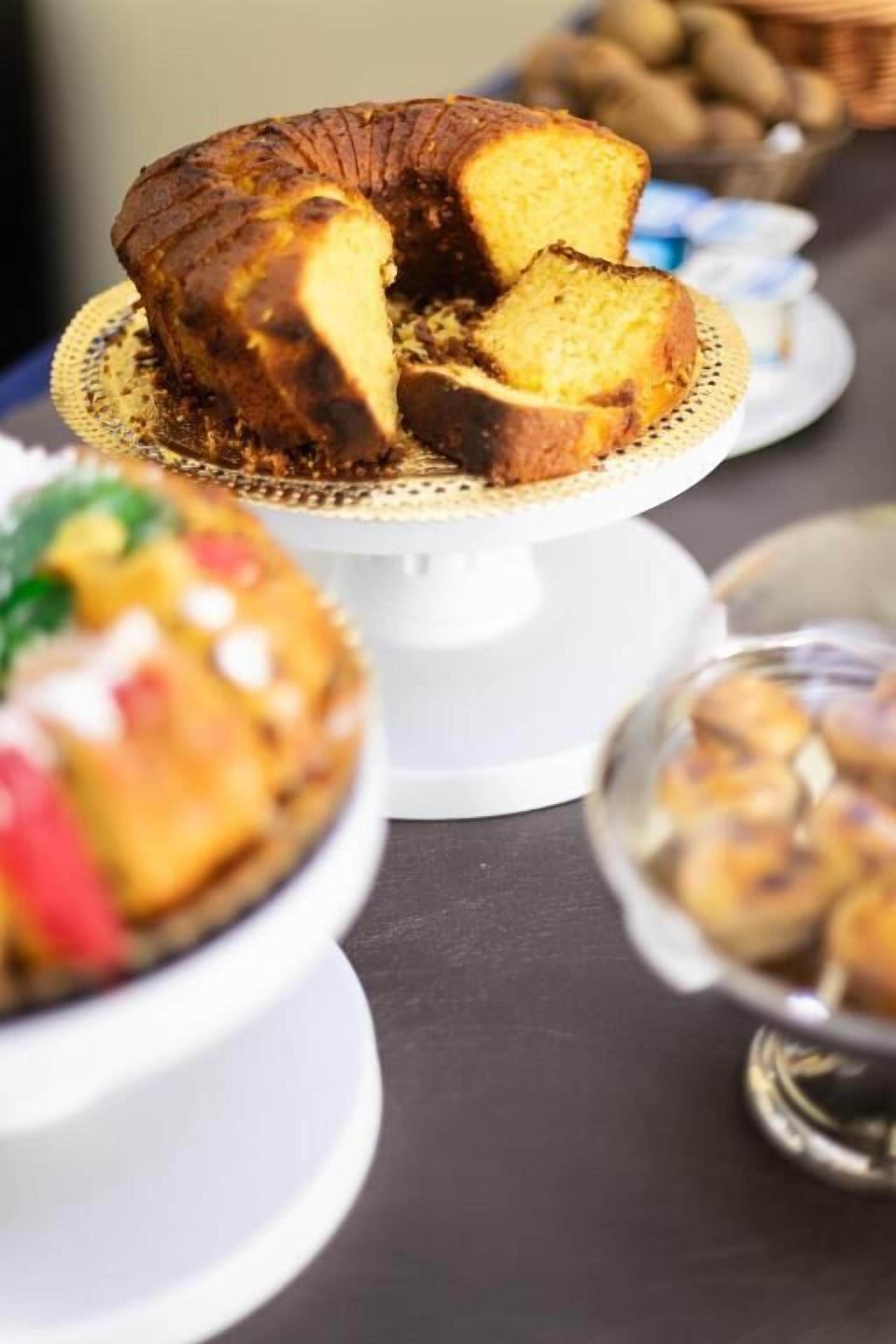 Taart op een wit plateau met gouden rand, omringd door andere desserts op een tafel.