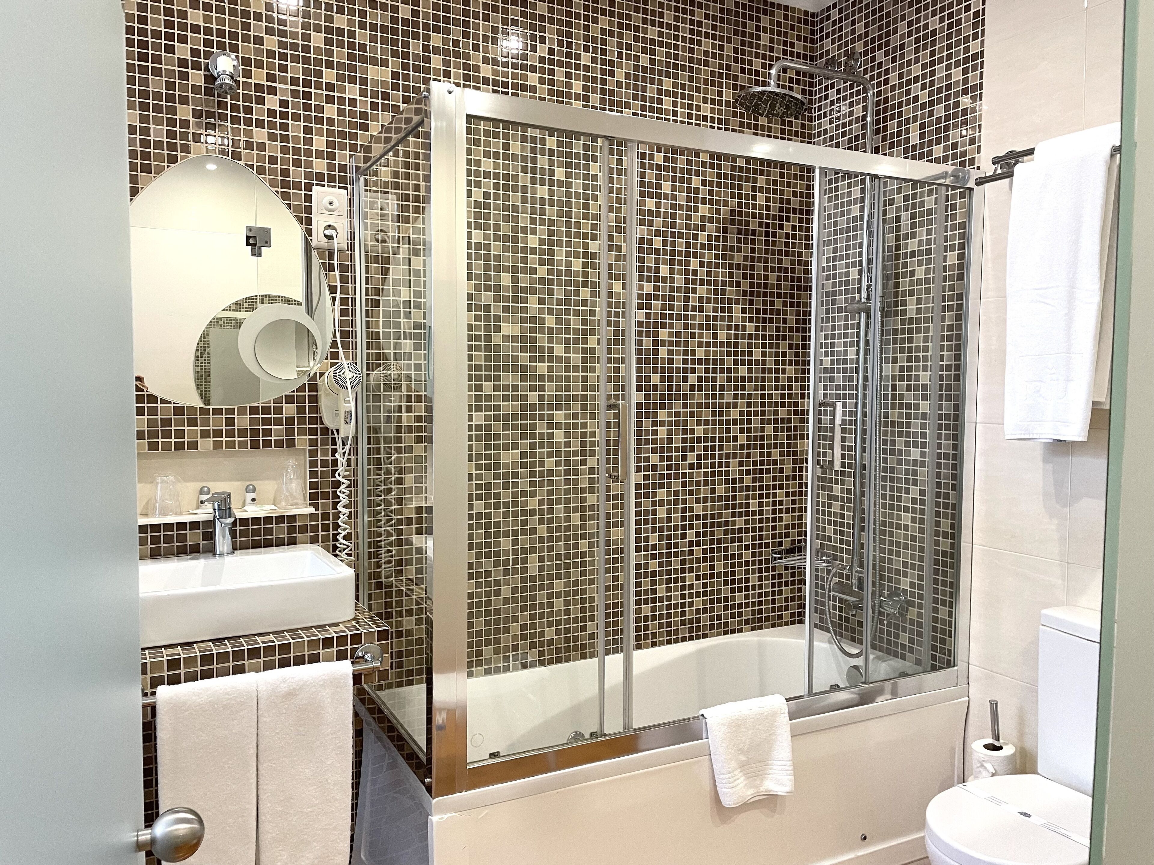 Un baño moderno con ducha de vidrio, un lavamanos blanco y un inodoro.