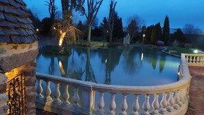 A serene outdoor pool area with a stone balustrade, a stone building, and trees in the background. - Oasis (Villaines-la-Juhel)