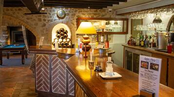 A bar area with a wooden counter, a lamp, and a wine rack.
