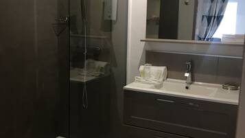 Une salle de bain moderne avec une douche à parois de verre, un meuble-lavabo avec un miroir et un évier.