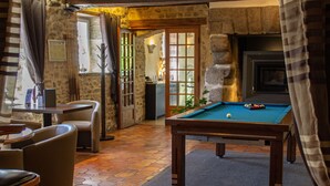 A billiards table in a room with stone walls, a fireplace, and a view through a door. - Oasis (Villaines-la-Juhel)