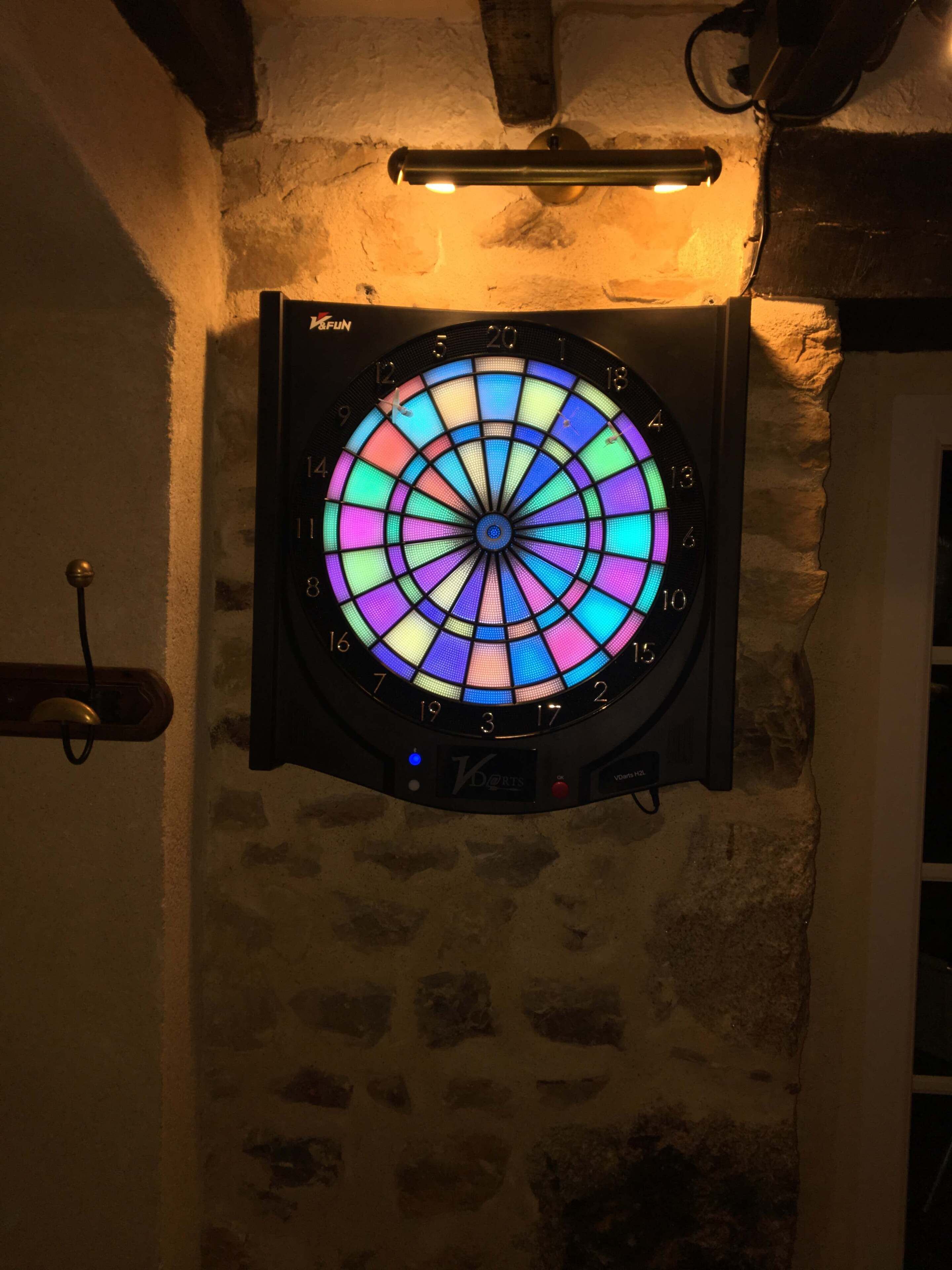 A dartboard mounted on a textured wall with a wooden beam above it.