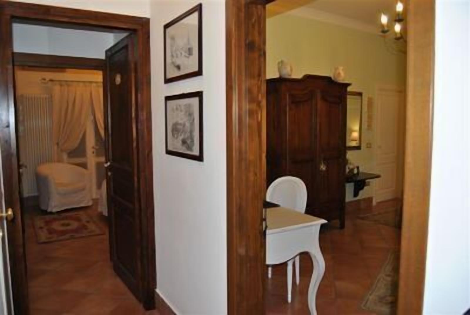 Un pasillo con una puerta de madera, una silla blanca y un armario.