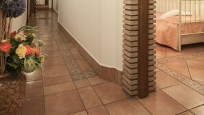 A hallway with a tiled floor, a wooden ceiling, and a bed with a metal frame in the room. - Mondo Antico Alloggio in Città B&B (Cesena)