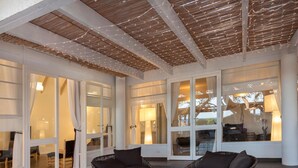 An indoor patio area with wicker furniture, large windows, and a wooden ceiling. - Hotel Mare Pineta (Pula)