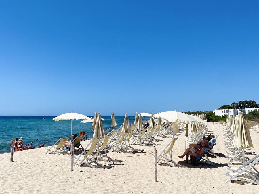 Na praia, areia branca, guarda-sóis