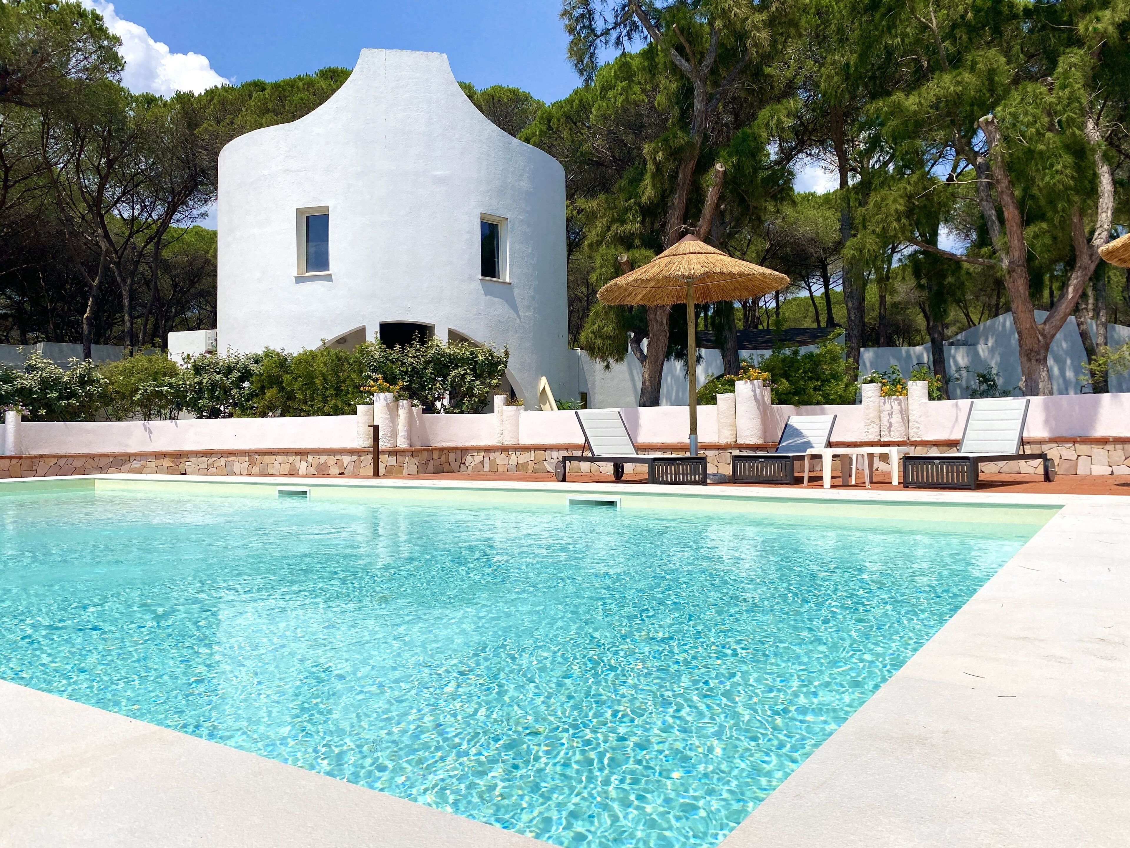 A swimming pool with lounge chairs and a white building in the background.