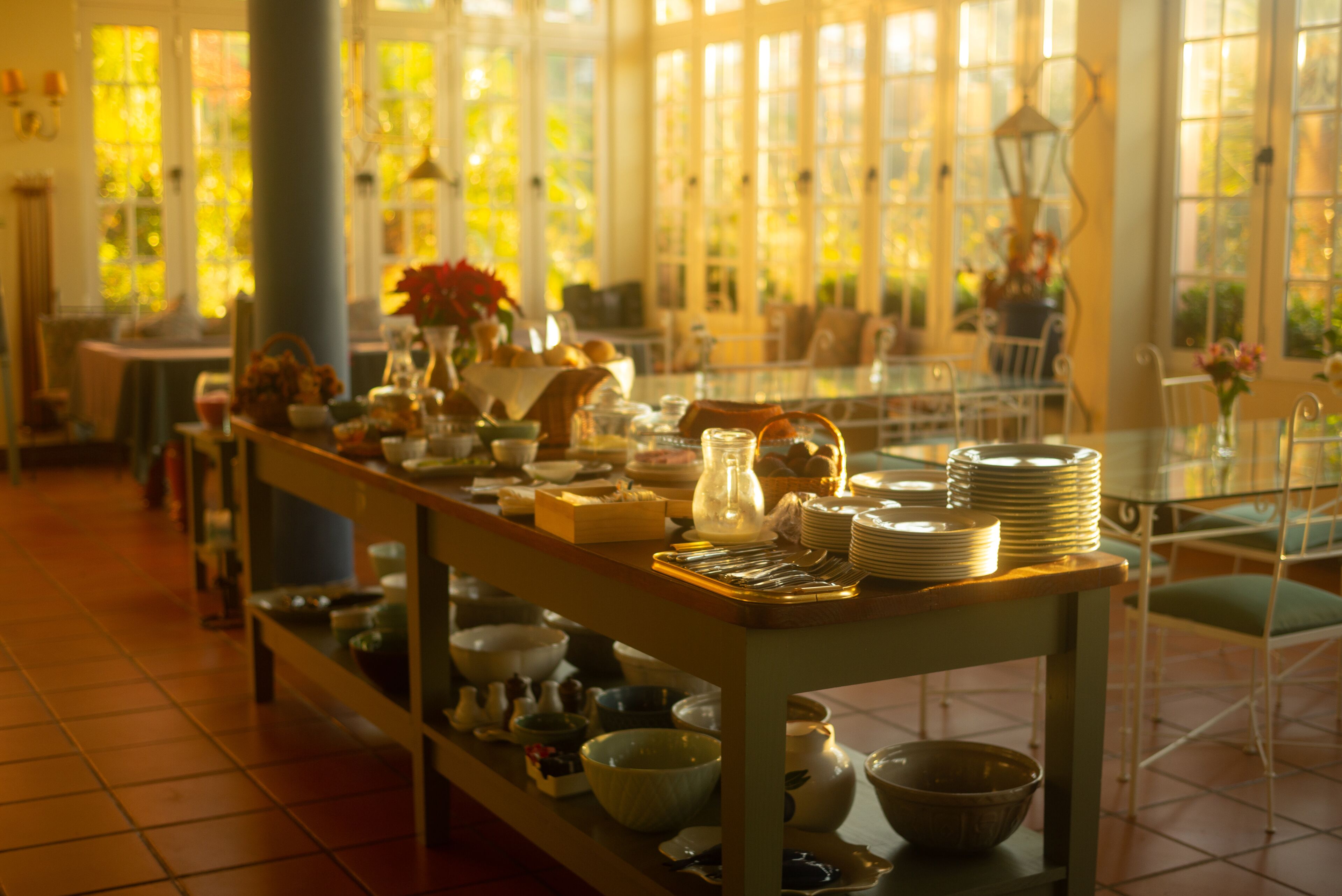 A dining area with a long table set with plates, bowls, and a variety of dishes.
