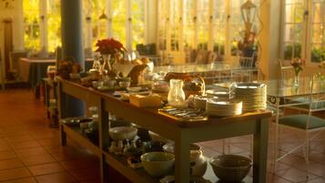 A dining area with a long table set with plates, bowls, and a variety of dishes.