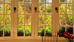 Una habitación con un ventanal grande que da a un jardín con diversas plantas y flores.
