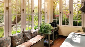 Una habitación con ventanas amplias, un sofá, una mesita con una planta y un armario.