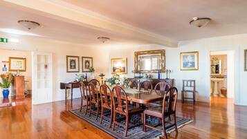 A dining room with a wooden table and chairs, surrounded by framed artwork and a chandelier.