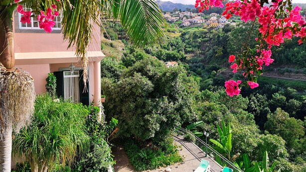 Una casa con balcón que domina un valle verde exuberante y un pueblo lejano.