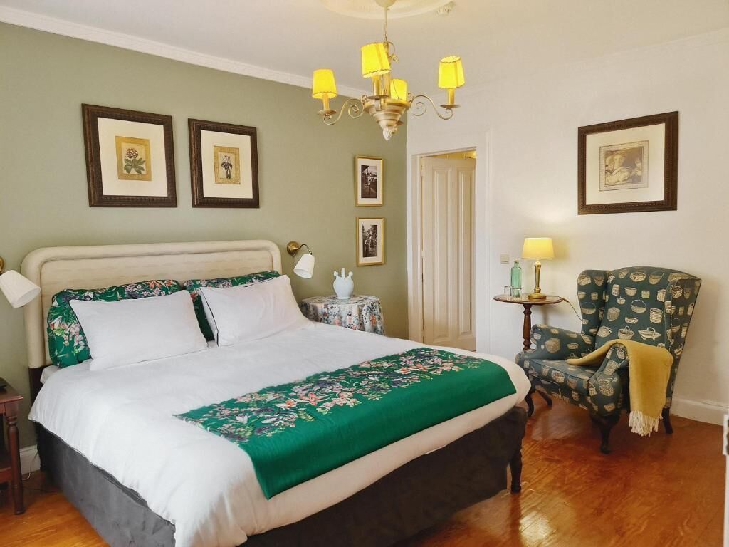 A bedroom with a bed, a chair, a table, and a chandelier.