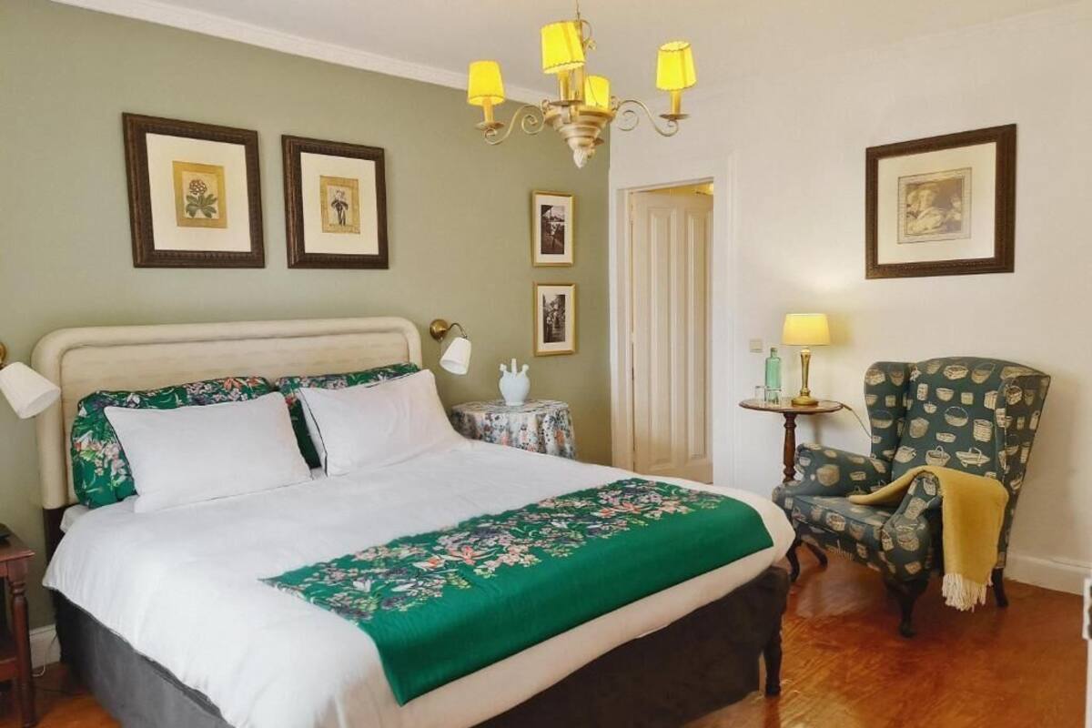 Un dormitorio con una cama, una silla, una mesa y una araña.