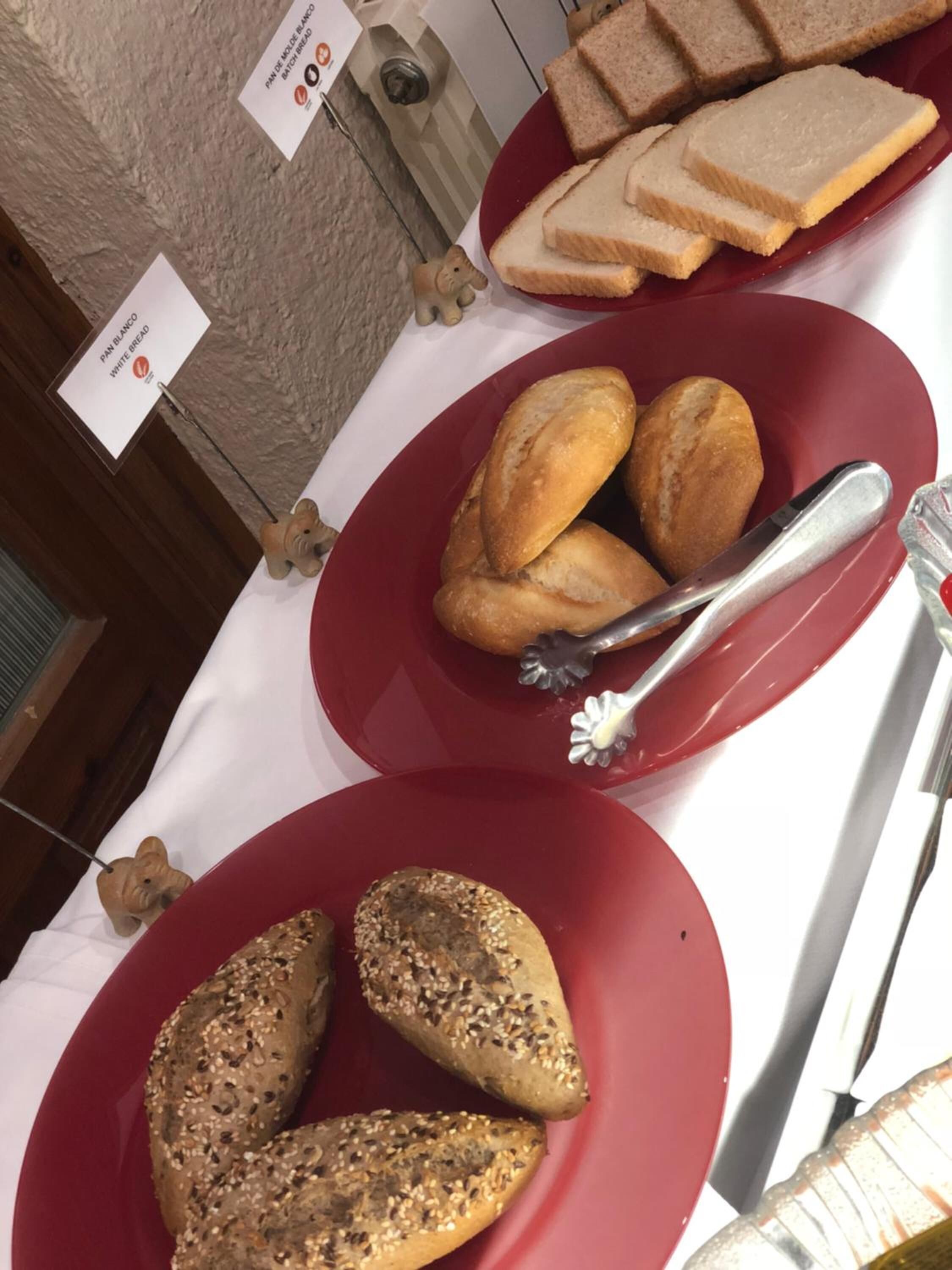 A table with red plates containing various breads and a knife with a fork.