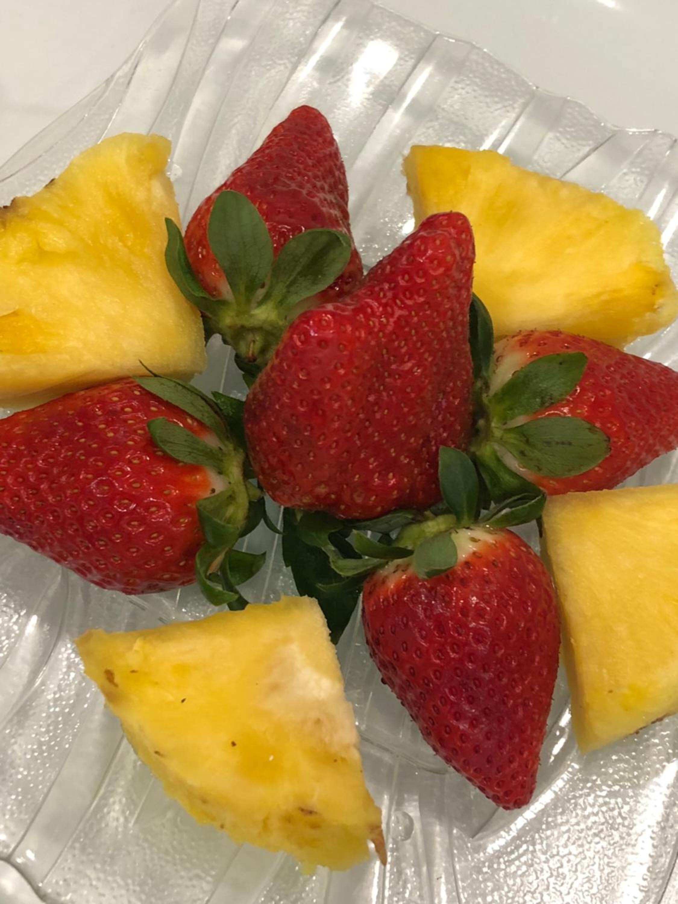 A glass plate with sliced pineapple and strawberries arranged in a circular pattern.