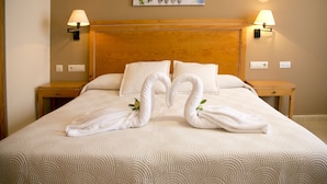 Una habitación de hotel con una cama grande, dos lámparas fijadas a la pared y un cuadro.