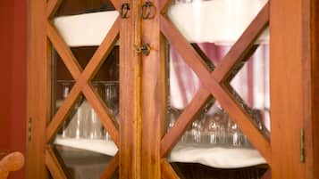 Un mueble de madera con puertas de cristal que contiene varios vasos de vino y un paño blanco.