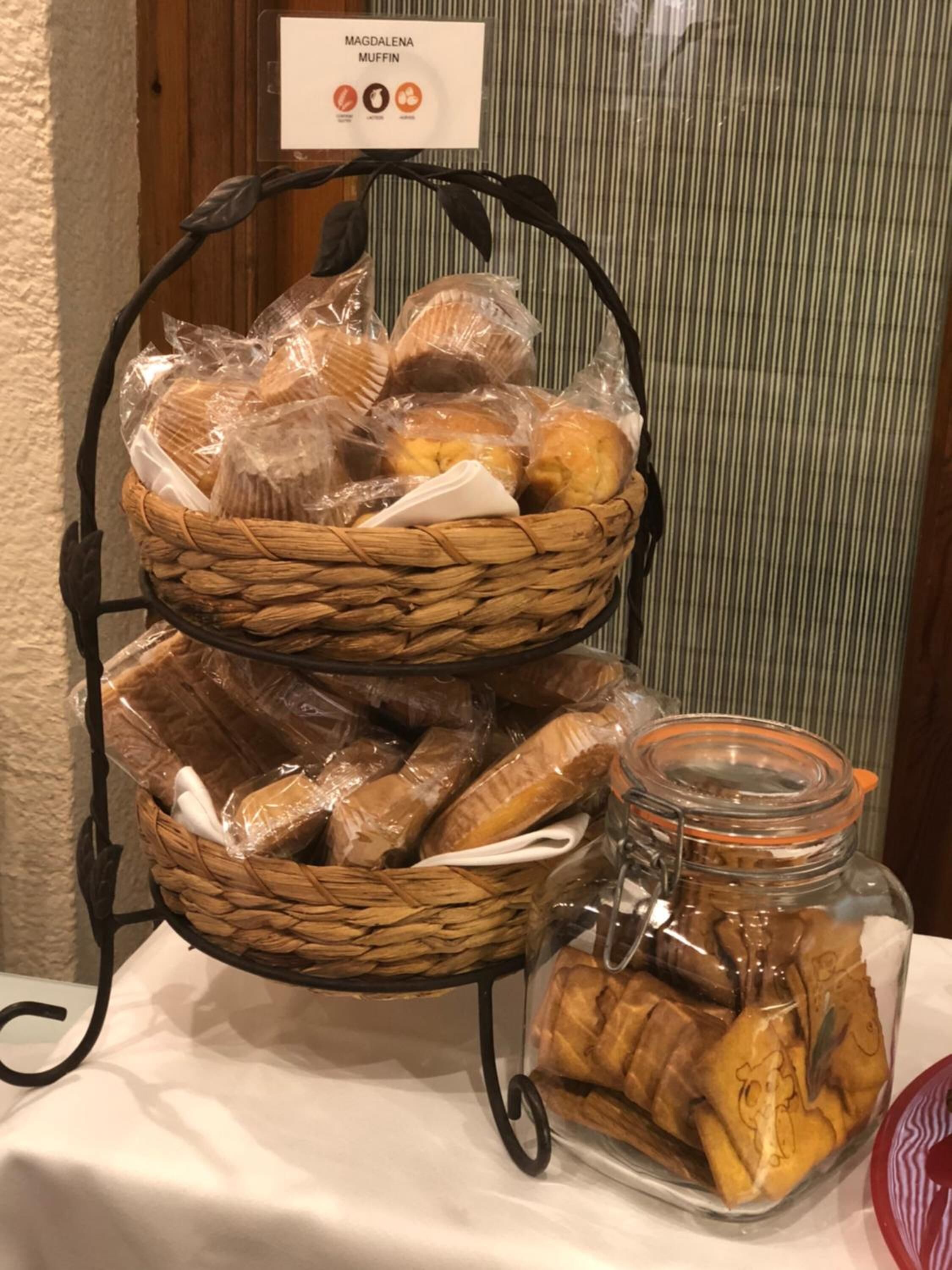 A display of baked goods including muffins and cookies in baskets and a jar.